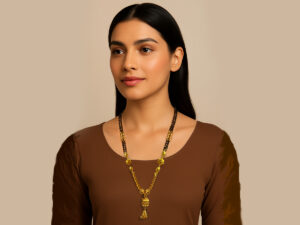 Gold-plated mangalsutra with a modern design, black beads, green and red gemstones, and a hanging golden tassel pendant.