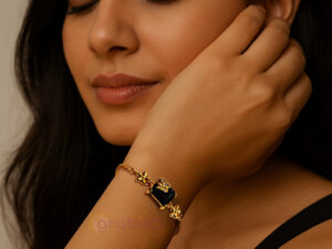 Gold-plated adjustable bracelet with black stone centerpiece and floral charms