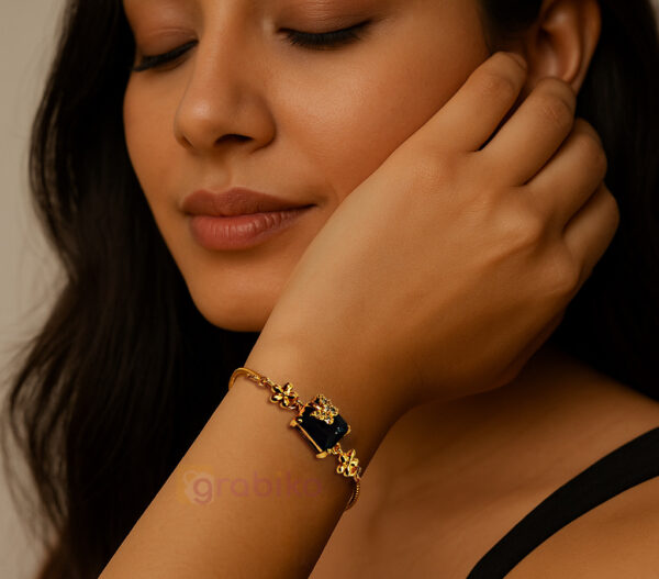 Gold-plated adjustable bracelet with black stone centerpiece and floral charms