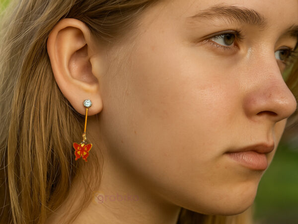 Elegant 3-pair earring combo with gold clover studs, red butterfly danglers, and pearl drop earrings.