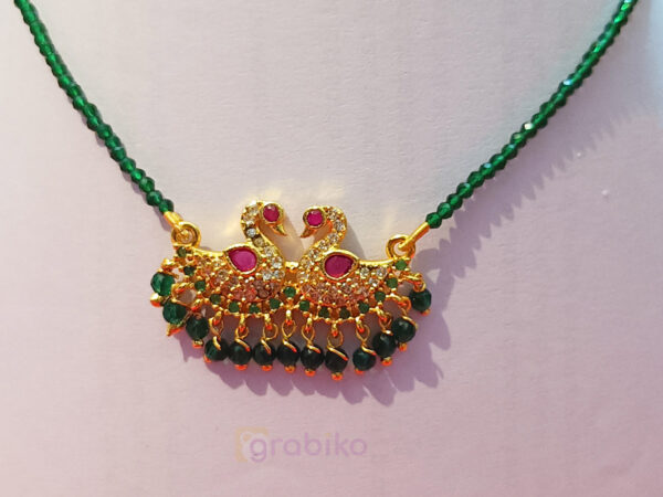 Elegant double peacock mangalsutra with CZ stones and green beads on pink fabric background