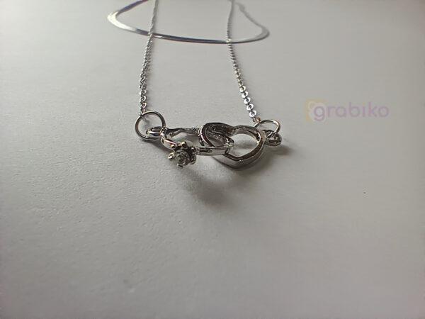Silver-tone double-layer necklace with snake chain, link chain, and interlocking rings pendant featuring a crystal accent.