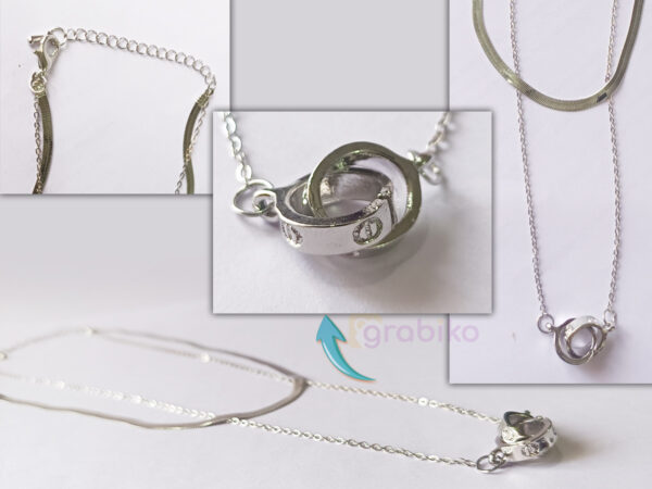 Double-layer silver necklace with snake chain, link chain, and interlocking ring pendant with crystals.