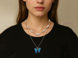 Two-layer necklace featuring a pearl choker chain and a long silver chain with a blue butterfly pendant, worn by a modern woman.
